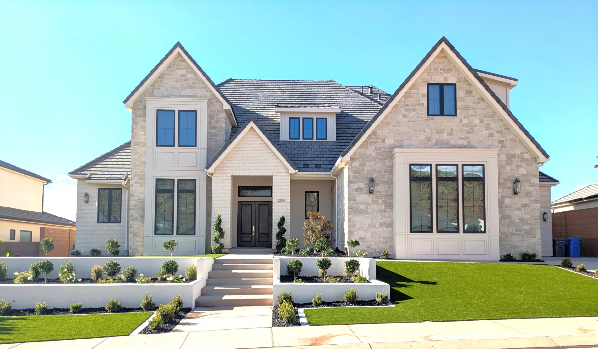 Teeples home with pale brick, steep gables, and a garden-lined front walk
