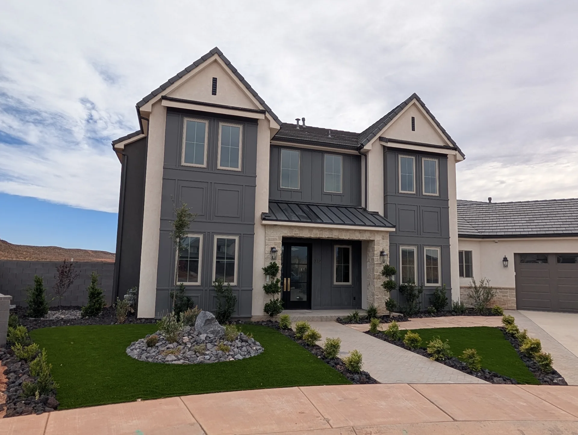 Two-story gabled home with dark siding and light stone