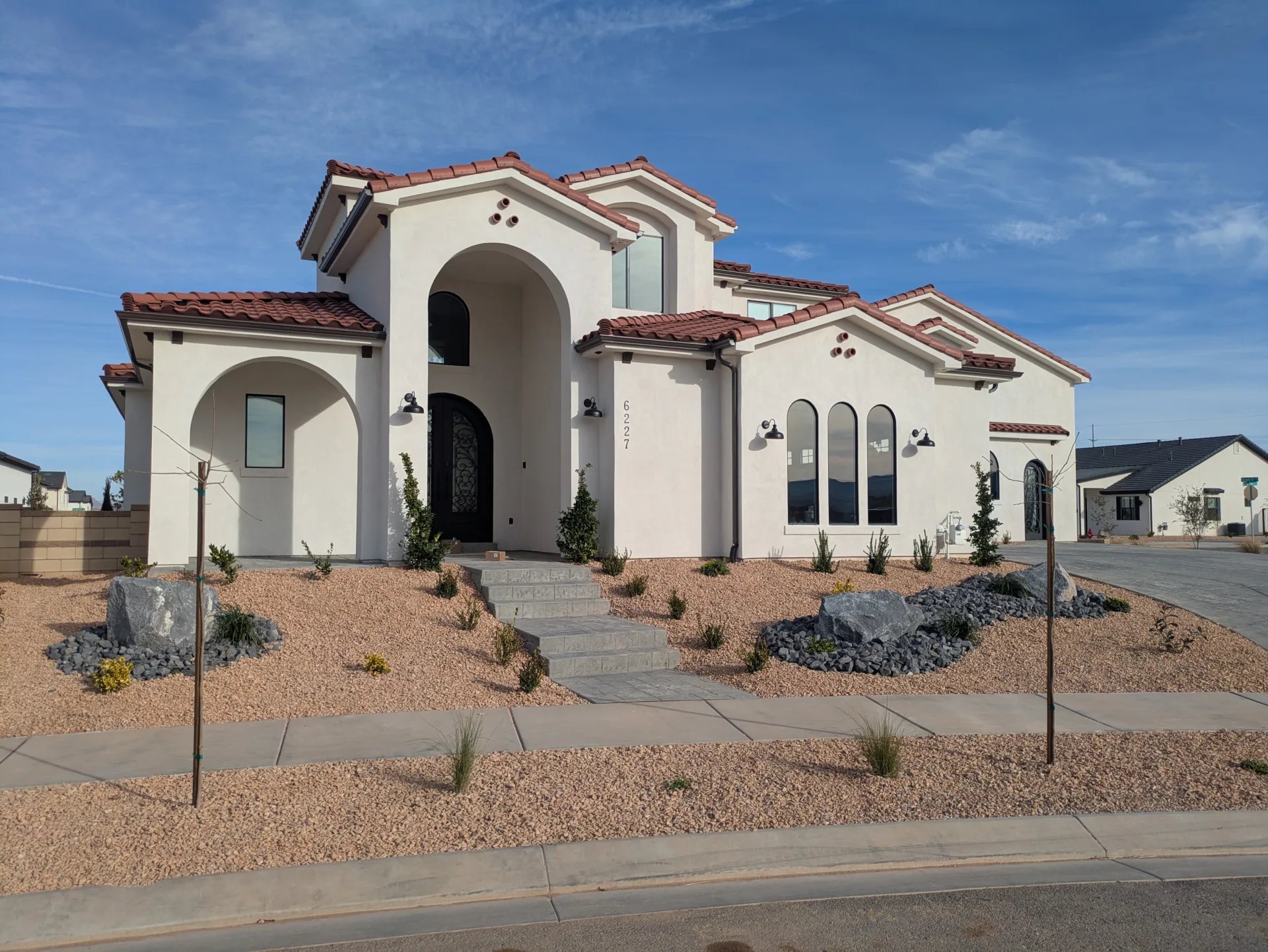 Stucco home with a tall arched entrance and red tile roof