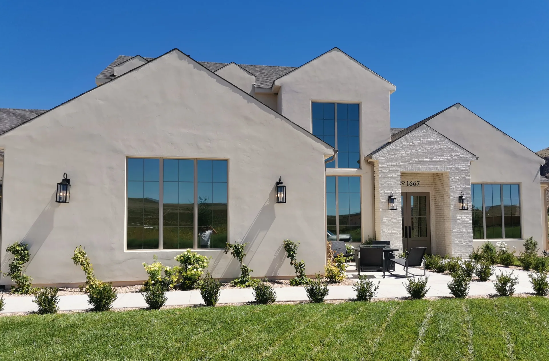 Pale stucco home with a tall front window and green lawn